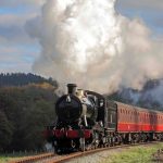 A vintage steam train travels alongside the River Dee on the Llangollen Railway.